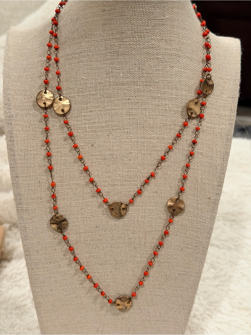 Long gold-toned necklace featuring small coral beads& textured circular stations